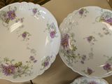 two plates with purple flowers on them are sitting on a table