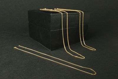 trois boîtes noires ornées de chaînes dorées sur fond noir