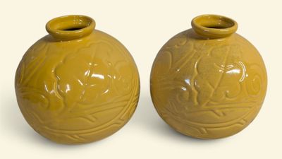 une paire de vases jaunes posés sur une surface blanche, sur fond blanc