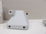 a polaroid camera sitting on a desk next to a remote control
