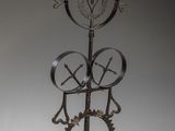 une sculpture représentant une horloge avec des rouages et une croix au sommet