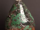 a glass bottle with green flowers on it sitting on a table