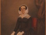 portrait d'une femme en robe noire, assise sur une chaise rouge