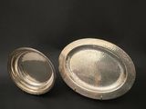 two silver trays sitting on top of a table next to each other