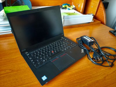 un ordinateur portable posé sur un bureau en bois, avec son chargeur