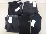 three pairs of black jeans and a black shirt on a couch