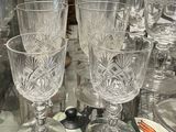 bottles and glasses on a table with a glass shelf in the background