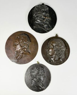 three bronze medallions of a man and a woman on a white surface