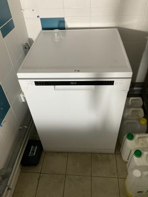 a small white dishwasher in the corner of a bathroom