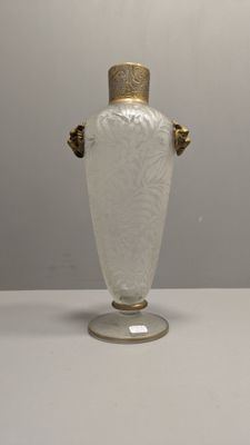 un vase blanc muni d'une anse dorée, posé sur une table