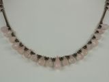 a close up of a necklace with pink beads on a white surface