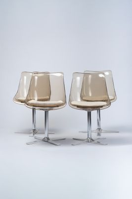 deux chaises en plastique transparent placées l'une à côté de l'autre sur une surface blanche