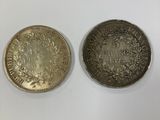 deux pièces d'argent et d'or posées sur une surface blanche