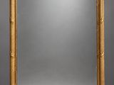 an ornately carved mirror with a gold frame on a grey background