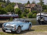 a blue sports car parked next to a boat on the water