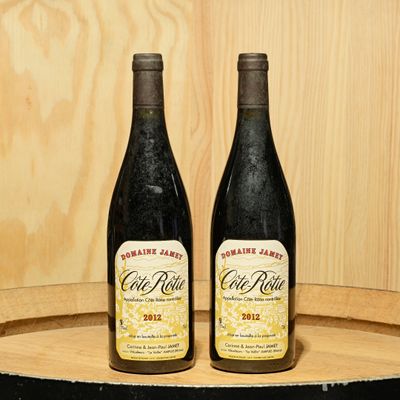 two bottles of wine sitting on top of a barrel