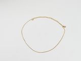 un bracelet en chaîne dorée orné d'une petite perle sur fond blanc