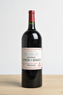 Une bouteille de vin rouge millésimé Château Lynch & Bages posée sur une table en bois