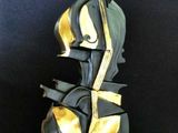 sculpture noire et dorée représentant un violon sur fond noir
