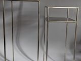 two metal stands with a glass top on a white surface