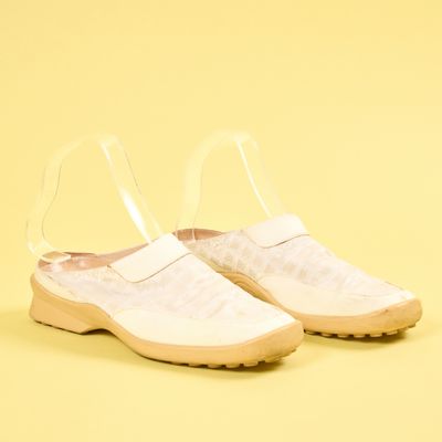 chaussures blanches à enfiler avec des lanières transparentes sur fond jaune