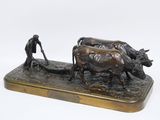 sculpture en bronze représentant un homme labourant un champ avec deux vaches