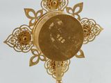 gold plated cross with ornate design on a stand on a white background