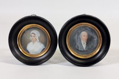 deux portraits encadrés représentant un homme et une femme, dans des cadres noirs et dorés