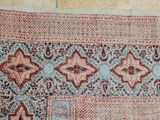 un vieux tapis aux motifs bleus et rouges posé sur un parquet