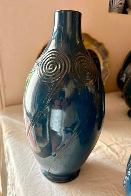 un vase bleu posé sur un lit, à côté d'un autre vase bleu
