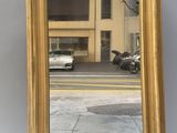 gold framed mirror on the side of a street with a motorcycle parked in front of it