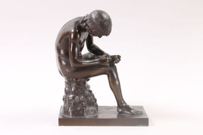 bronze statue of a man sitting on a rock with his hands on his knees