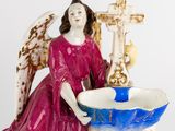a figurine of an angel with a cross and a bowl