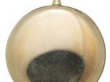 a gold pocket watch with a black spot on it