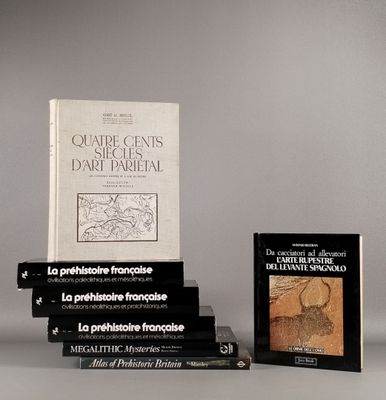 Plusieurs livres sont empilés les uns sur les autres devant un fond gris.