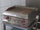 stainless steel counter top with a griddle on it in a commercial kitchen