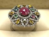 un gros plan d'une bague ornée d'une pierre rose entourée de pierres multicolores