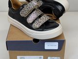 des baskets noires à imprimé léopard, avec des semelles blanches, posées sur une boîte en carton