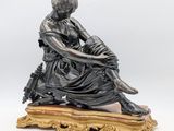 an antique bronze figurine of a woman sitting on a wooden base