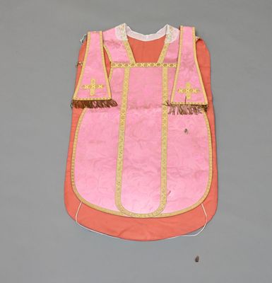 a pink vest with gold trim on a gray surface