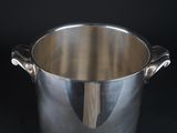 a silver pot with a handle on a black table
