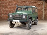 a green land rover parked in front of a brick wall