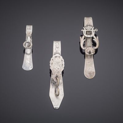 three pieces of silverware on a gray surface with a black background