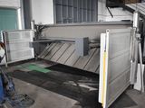 a machine that is cutting a sheet of metal in a factory