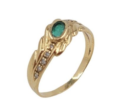 gros plan d'une bague en or avec une pierre verte