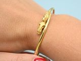 a close up of a person ' s hand with a red manicure and a gold bracelet