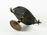 a small black object with a gold rim on a white surface