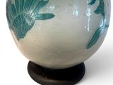 a white and blue vase with green leaves on it