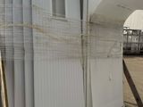 many white refrigerators stacked on a pallet in a warehouse