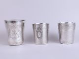 three silver cups sitting next to each other on a white surface
